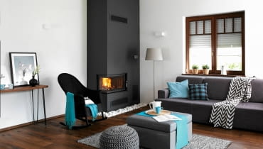 <B>Wizja nadchodzących chłodów zmobilizowała Anię i Marcina do zamontowania kominka, na który czekało już dawno przygotowane miejsce w salonie. Ta zmiana pociągnęła za sobą drugą, nie mniej istotną - dokończono aranżację całego wnętrza, nadając mu spójny, a do tego bardzo efektowny styl.</B> <BR />PO ZMIANIE. Gospodarze sami wybrali wkład i?zaprojektowali jego obudowę. Pomalowali ją na?odcień grafitowej szarości kontrastujący z?bielą ściany. Wybrali bardzo odporną na?szorowanie farbę ceramiczną, tak?by można było usuwać na mokro wszelkie osady i plamy. O dobranie pozostałych elementów wystroju poprosili stylistkę. Zaproponowane przez nią meble i dekoracyjne dodatki znakomicie wkomponowały się w minimalistyczny styl pokoju, przełamując zarazem jego dotychczasową surowość. aranżacja salonu, metamorfoza salonu