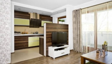 Salon. W otwartym wnętrzu panele położono tylko w części wypoczynkowej; w aneksie kuchennym są łatwe do utrzymania w czystości płytki ceramiczne. Miejsce styku tych dwóch różnych materiałów zostało zamaskowane listwą. WNETRZA , POKOJ , SALON , PODLOGA - PANELE LAMINOWANE