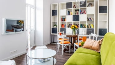 Otwarta strefa dzienna łączy salon i jadalnię. Tak jak w całym wnętrzu, tak i tu dominuje czysta biel. Ożywczy kolor wnosi kanapa z tapicerką w świeżym zielonym odcieniu. salon, wystrój wnętrz, mieszkanie, aranżacja wnętrz