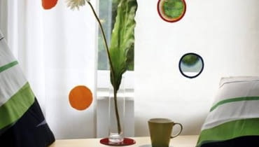 ZNISZCZONA ZASŁONA. Nawet niewielkie uszkodzenie na zasłonie, zwłaszcza podświetlone promieniami słońca, staje się bardzo widoczne. Cerować jej nie radzimy, bo to również nie wygląda dobrze. Proponujemy inny sposób. W miejscu uszkodzenia wycinamy kółko. Takie same otwory robimy w regularnych odstępach na całej zasłonie. Brzegi otworów obszywamy lamówkami ze skosu (w jednym kolorze lub w kilku). Dla przeciwwagi na drugą zasłonę naszywamy kółka wycięte z kolorowych tkanin, takiej samej wielkości jak otwory. Cena nowej zasłony: ok. 150 zł. Koszt naprawy: 16 zł (cena lamówki: 4 zł/m). OSZCZĘDZASZ 134 zł.