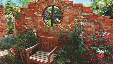 Ogrodowa klasyka - ścianka z cegły. Aby nie zamykała widoku na ogród, pozostawiono w niej otwór na okno.