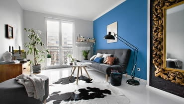 Największą ozdoba pokoju dziennego, urządzonego w eklektycznym stylu, jest duże lustro w ramie bogato zdobionej złoceniami i snycerką (rzeźbieniami). Jego urodę podkreśla tło - pomalowana na czarno cegła odkryta na fragmencie ściany. pokój dzienny, salon, wystrój wnętrz, nowoczesne wnętrza