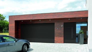 Brama garażowa i drzwi, umieszczone na elewacji blisko siebie, utrzymane są w tym samym stylu i kolorystyce Brama garażowa i drzwi, umieszczone na elewacji blisko siebie, utrzymane są w tym samym stylu i kolorystyce