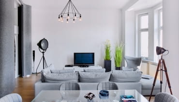 Monochromatyczna aranżacja świetnie komponuje się z wnętrzami o ponad stuletnim rodowodzie. Lampy na trójnogach pochodzą ze sklepu Brocante Warszawski.