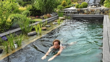 Schwimmteich/ Swimmingpool mit Filterzone und Terrasse im Hintergrund und schwimmender m nnlicher Person. SLOWA KLUCZOWE: Bockholt Deutschland Filterzone Fitnessgarten FocusOnGarden Garten Gartenebene Gartenfeature Gartenreportage Gartenreportage Bockholt gartenteich Hausgarten J´rgen Becker Leute Mann Mensch modern Moderner Garten People pflegeleichter Garten pool Schwimmteich Schwimmteich mit Filterzone Sommer swimming pool wasser Wassergarten Ziergarten Querformat