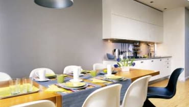 <b>Do spotkań przy stole</b> Kuchnia została zabudowana jednym rzędem szafek; górne sięgają do samego sufitu. Fronty są białe, natomiast kolor blatu, uchwytówi cokołu dopasowano do barwy ściany. Wyeksponowano stół, przy którym spotyka się rodzina