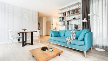 W salonie główną rolę odgrywa sofa w wyszukanym, błękitnym odcieniu. Cozy Nordic Home czyli przytulne mieszkanie z kotem w tle