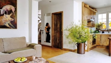 Aranżacje. Proste meble z drewna, ceramiczne ozdoby i gliniane naczynia z polnymi kwiatami, a w kuchni zapach przetworów. Wchodząc do tego domu, zapominamy o dużym mieście tuż za ogrodzeniem. Wkraczamy w świat, o jakim marzą mieszczuchy.<BR />Stolik kawowy z litego drewna ma oryginalną rzeźbioną dekorację - takie meble artystka nazywa meblorzeźbami. Na podłodze w całym domu ułożono deski bukowe z widocznymi sękami (tylko do kuchni wybrano gres przypominający fakturą kamień). W wielkim glinianym naczyniu zawsze stoją bukiety nawiązujące do pory roku. UWAGA ! PONOWNA PUBLIKACJA WYLACZNIE ZA ZGODA WLASCICIELI