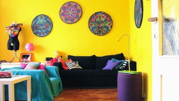 30-metrowa kawalerka została utrzymana w intensywnych odcieniach, z których najbardziej wybija się słoneczny żółty kolor. kawalerka, małe mieszkanie, kolory we wnętrzu, ludowe dekoracje