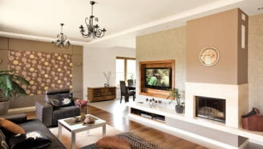 Aranżacje. Marzena i Jarek lubią swój dom z kilku powodów. Po pierwsze, przez okna salonu mogą oglądać sarny wychodzące na brzeg znajdującego się nieopodal lasu. Po drugie, wnętrza są bardzo przestronne i pełne światła. Po trzecie, dom jest parterowy, nie martwią się więc, że mała Zuzia i Jędrzej biegają po schodach.<BR />W salonie uwagę zwraca kącik telewizyjno-kominkowy. Obudowa kominka jest zrobiona z jasnego trawertynu. Płaski ekran, zawieszony we wnęce wykończonej palisandrem, wygląda jak obraz w ramie. Obraz przypomina również dekoracja w aneksie wypoczynkowym: obramowana płytą gipsowo-kartonową tapeta w kwiaty - motyw konsekwentnie powtarzający się we wszystkich pomieszczeniach.