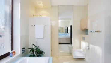 <B>Z wyborem kabiny, w której zamiast tradycyjnego brodzika jest odpowiednio wyprofilowana podłoga, wiąże się wiele korzyści: większa swoboda w decydowaniu o jej kształcie i brak progu w wejściu; poza tym łazienka wydaje się przestronniejsza. Aby takie rozwiązanie sprawdziło się w praktyce, ważne jest skuteczne odprowadzenie wody.</B> <BR >ŁAZIENKA: Z KABINĄ NA MIARĘ. Chociaż na rynku są dostępne kabiny prysznicowe o różnych kształtach i wielkościach, w nowo projektowanych łazienkach coraz częściej pojawiają się kabiny murowane. Za takim wyborem przemawia łatwość wygospodarowania miejsca na natrysk i większe możliwości indywidualnej aranżacji wnętrza. <BR >Ściankę kabiny wyłożono białą mozaiką; z niej zrobiono także obramowanie wysokiego lustra (taflę przyklejono bezpośrednio do ściany) i cokół przy podłodze. We wnęce nad podwieszanym sedesem zawieszono praktyczną szafkę z płyty fornirowanej bielonym dębem.