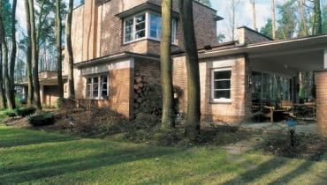 Widok na dom od strony ogrodu. Architekci dołożyli starań, by podkreślić urodę leśnego otoczenia budynku. Kształty elewacji i formę domu 'wpisano' pomiędzy rosnące wokół sosny i dęby.