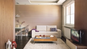 Pani Iwona mieszka teraz w Brukseli, jednak w Warszawie czeka na nią odnowione mieszkanie. To jej azyl, miejsce do życia na stałe. Urządzaniem wnętrz zajęła się projektantka, a większość rzeczy niezbędnych w nowym domu gospodyni kupiła w internecie i zobaczyła dopiero, gdy mieszkanie było już gotowe. <BR /> MIESZKANIE. W salonie dominują brązy i beże z elementami złamanej bieli. Fragmenty ścian wykończono fornirem z drewna orzecha amerykańskiego, a podłogę - trwałym i dekoracyjnym parkietem przemysłowym z czarnego dębu wędzonego. Ściana nad kanapą jest wyłożona szerokimi pozio- mymi pasami z płyt gipsowo-kartonowych.