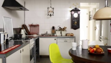 Ściana wyłożona białymi płytkami ceramicznymi straciła nieco swój "szpitalny" charakter, gdy zawieszono na niej stary zegar. Na jej tle znakomicie prezentuje się również oryginalna lampa sufitowa. WNETRZA LACZENIE STYLOW KUCHNIA MEBLE