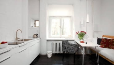 Kuchnia w wariancie 1. Na podłodze - pomalowane na czarno deski, na ścianie przy kuchennych szafkach - cegły pokryte białą farbą. Właścicielce zależało, by zachować jak najwięcej oryginalnych elementów wnętrza. Zmieniła więc tylko nieco ich wygląd.