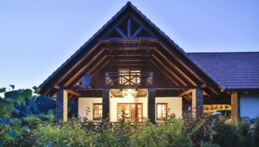 Silnie wysunięty dach, wsparty na kamiennych słupach, w niepogodę osłania balkon i taras przed opadami, a w upalne dni chroni korzystających z nich domowników przed intensywnym słońcem dom w nocy, elewacja ogrodowa, dach