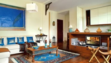 WNĘTRZA. Gdyby scenograf szukał rekwizytów do filmu o egzotycznych krainach, mieszkanie pani Iwony byłoby dla niego prawdziwym sezamem - znalazłby tu autentyczne wschodnie meble i dodatki wprost z arabskich sklepików. Tylko za oknem... warszawski Mokotów zamiast pustyni.<BR /> Pokój dzienny jest połączony z kuchnią (to jedna ze zmian przeprowadzonych przez gospodynię po kupieniu mieszkania). Biel ścian efektownie kontrastuje z ciemnymi meblami, a zarazem optycznie rozjaśnia pomieszczenia. Na podłodze olejowane i lakierowane drewno merbau (olej pogłębia kolor drewna, lakier zaś je chroni). wystrój wnętrz, aranżacja wnętrz, salon