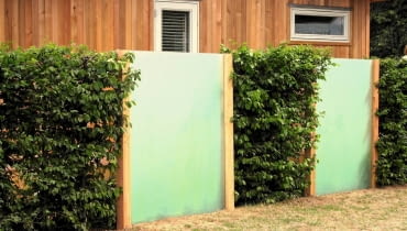 Ogrodzenie ze stalowej siatki (skrytej pod gałązkami formowanych krzewów) i tafli z tworzywa sztucznego, imitujących mleczne szkło. Ogrodzenie ze stalowej siatki (skrytej pod gałązkami formowanych krzewów) i tafli z tworzywa sztucznego, imitujących mleczne szkło.