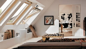 <B> Wnętrza ze skosami mają wiele uroku, często jednak brak nam pomysłu, jak praktycznie zagospodarować kłopotliwe zakamarki pod pochyłym dachem, zwykle z oknem dachowym. Poznajcie nasze propozycje. </B><BR /> Specjalista Justyna Burdow-Gołoś Architekt Wnętrz radzi: <BR /> Aby jak najlepiej wykorzystać przestrzeń pod skosami, warto pamiętać o kilku zasadach. Okna połaciowe dobrze oświetlają wnętrze, gdyż światło wpadające pod kątem i z góry jest bardzo jasne. Standardowa wysokość takich okien wynosi od 80 do 120 centymetrów, ważniejsza jednak jest wysokość, na której są umieszczone. Jeśli będą zbyt nisko, wpuszczą mniej światła, a do tych zamontowanych zbyt wysoko będziemy mieć trudny dostęp, co ma znaczenie przy ich otwieraniu i myciu. Elementy konstrukcyjne (belki, słupy, podciągi) nie powinny być przestawiane ani likwidowane bez uprzedniej konsultacji z fachowcem. Pamiętajmy o tym na etapie planowania przestrzeni. Zamiast zmieniać położenie tych elementów, lepiej wykorzystać je w aranżacji - na przykład obudować zawsze przydatnymi półkami czy szafkami. Skosy sięgające podłogi warto zabudować niską ścianką, przy której łatwiej będzie ustawić meble. W takiej przegrodzie można również zamontować drzwiczki - wtedy przestrzeń za nią stanie się dodatkowym schowkiem. <BR /> ARANŻACJA WNĘTRZ. Podręczna biblioteczka. Wzdłuż ściany z oknami połaciowymi zaprojektowano półkę. Stoją na niej nie tylko ozdobne drobiazgi, ale również książki. Zabudowę zrobiono z płyty gipsowo-kartonowej. Belkę konstrukcyjną pozostawiono odkrytą - taka dekoracja bardzo pasuje do tego wnętrza.