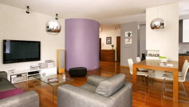 <B>Wielu projektantów uważa, że w każdym mieszkaniu powinno być jakieś oryginalne rozwiązanie, mebel lub urządzenie - coś, co będzie przyciągać uwagę i kojarzyć się z wnętrzem. W tym przypadku jest to garderoba o ciekawej formie walca.</B> <BR />Ściana, na której zawieszono telewizor, to pomalowana na biało cegła. Taką samą gospodarze mieli w poprzednim mieszkaniu, poprosili więc projektantkę, by w nowym uwzględniła takie rozwiązanie.