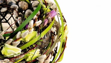 WIENIEC Z BAZAMI I KWIATAMI Jego podstawę stanowi kolista konstrukcja z drutu, pomiędzy który wpleciono bazie, tulipany, frezje, trzcinę, trawę i doklejono sztuczne jajka.