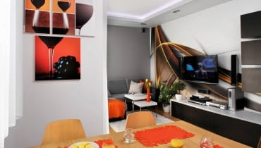 <B>Gdy Karina i Mariusz ujrzeli przed budynkiem park pełen jesiennych barw, kupili mieszkanie bez chwili zastanowienia. Uroda październikowej przyrody zainspirowała ich także do wyboru kolorystyki wnętrz. Ubrali je w oranże, rudości i czerwienie - tak jaskrawe, że wydają się płonąć na neutralnym tle.</B> <BR />Pokój połączono z kuchnią, pozostawiając tylko wąską ściankę. Dzięki tej przebudowie gospodarze zyskali w miarę przestronną strefę dzienną, którą zaaranżowali w&#8200;jednakowym stylu i&#8200;kolorystyce. Ważną dekoracją wnętrza jest&#8200;naklejona na&#8200;jedną ze ścian fototapeta z&#8200;abstrakcyjnym motywem. Do jej barw dobrano obrazy wiszące w kuchni.