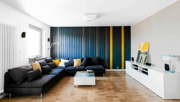 <B>Mieszkanie w bloku z wielkiej płyty nie było dla gospodarzy przykrą koniecznością. Wybrali je, bo nie kusiła ich wizja w pilnie strzeżonym, luksusowym apartamentowcu, a taką właśnie mieli alternatywę. Chociaż zmodernizowali wnętrza, wprowadzając je w XXI wiek, zachowali dużo elementów świadczących o rodowodzie i konstrukcji budynku.</B> <BR />Wielkość pokoju dziennego odbiega od PRL-owskich standardów. Nic dziwnego, powstał z połączenia dwóch mniejszych pokoi. Do lat siedemdziesiątych nawiązuje natomiast drewniana boazeria na ścianie, modna w owych czasach. Tu wygląda jednak nowocześnie, bo pomalowano ją w nieregularne pasy w trzech kolorach.