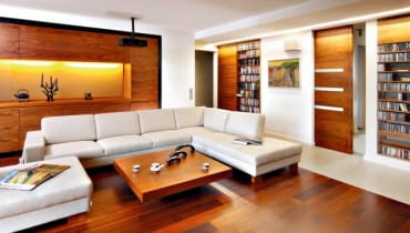 <b> ŁADNIE SCHOWANE. Szafki i regały w salonie powinny nie tylko dobrze spełniać swoją funkcję, ale i estetycznie wyglądać. A to zależy od formy mebli oraz materiału, z jakiego są zrobione. </b> <BR /> Właścicielom, kinomanom i melomanom z zamiłowania, zależało na przechowywaniu w salonie bogatych zbiorów filmów i płyt muzycznych. Potrzebowali więc pojemnych schowków, ale takich, które nie dominowałyby nad wypoczynkową funkcją pomieszczenia. Projektanci zaproponowali zbudowanie w ściennych wnękach otwartych półek na płyty CD i DVD, które prezentują się efektownie, oraz zamykanych szafek na rzeczy nie do eksponowania. Zabudowa okazała się trafionym pomysłem - nie przytłacza wnętrza tak jak masywne wolno stojące meble. Lekka forma schowków idzie w parze z urodą drewna orzechowego, z jakiego zostały zrobione. <BR /> Kredens w nowoczesnym wydaniu. Obszerną wnękę w jednej ze ścian zabudowano szafkami zamykanymi pełnymi drzwiczkami bez uchwytów. We wnęce w środku tej zabudowy gospodarze eksponują dekoracyjne drobiazgi.