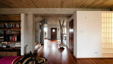 Betonowe sufity, odsłonięte słupy konstrukcyjne i ceglane ściany zmieniły mieszkanie w tradycyjnym szeregowcu w nowoczesne, przestronne wnętrza nawiązujące do stylu loftów. A jednak ten dom jest pozbawiony charakterystycznej dla nich surowości. Pan Robert, właściciel, a zarazem projektant, ocieplił go drewnem, tkaninami i obrazami własnego autorstwa. <BR /> DOM. Łazienka została urządzona w kubiku, na którego suficie chętnie wylegują się domowe koty. Jedną ze ścian częściowo przeszklono luksferami, dzięki czemu do pomieszczenia wpada naturalne światło.