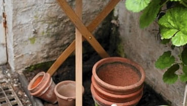 Mycie donic. Donic glinianych można używać wielokrotnie, ale wcześniej trzeba je wyczyścić i zdezynfekować Wooden Table with Cut Flowers and Garden String with Terracotta Plant Pots and Geranium Foliage (Pelargonium)