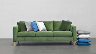 Sofa Kera to połączenie prostej formy i wygody. Występuje w różnych rozmiarach i obiciach, m.in. w aksamitnej tkaninie o głębokim odcieniu zieleni.