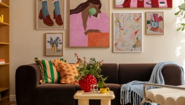 Wieloelementowa kolekcja obrazów w tej aranżacji tworzy spójną całość dzięki zbliżonej kolorystyce i klimatowi vintage. Zarówno na płótnach, jak i w całym salonie wyczuwalna jest swobodna, radosna energia.