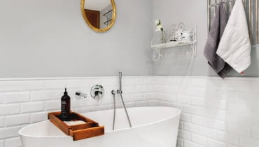 Kącik z wanną wygląda bardzo stylowo. Uwagę zwracają wzorzyste płytki na podłodze (gres z serii Llagostera firmy Vives Ceramica). Ściany chroni przed zachlapaniem lamperia z płytek. Jest tu też stare lustro w ramie pomalowanej na złoty kolor i postarzana półka-wieszak. Grzejnik wygląda jak kratka, po której zaraz zacznie się piąć dzikie wino. Nad wanną zainstalowano baterię podtynkową. Łazienka, wanna , Vives Ceramica, płytki łazienkowe, łazienka z wanną