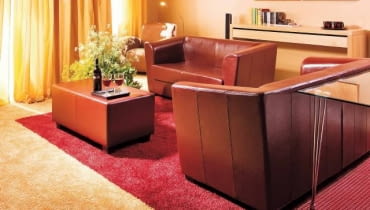 Salon. Kontrastowe barwy dwóch wykładzin dywanowych nawiązują do kolorystyki całego wnętrza. Do aneksu wypoczynkowego wybrano czerwoną; taki kolor ma też sufit podwieszany i klosze wiszących lamp. WNETRZA , POKOJ , SALON , PODLOGA - WYKLADZINA DYWANOWA