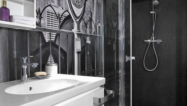 <B>Łazienka cała wyłożona kafelkami jest już raczej nie na czasie. Ale jeśli oprócz ceramiki pojawią się w niej inne materiały, trafi wysoko na?listę?modnych rozwiązań. Oto trzy wnętrza, w których płytki mają dobre towarzystwo.</B> <BR />WNĘTRZE 1 - FOTOTAPETA I FORNIR. Łazienka jest utrzymana w kontrastowej, czarno-białej kolorystyce, nawiązującej do wystroju reszty domu. Stąd m.in. gresowa szachownica (10 x 10 cm) na podłodze - identyczna znajduje się w kuchni i?korytarzu. Z pomieszczenia korzysta osoba niepełnosprawna poruszająca się na wózku, dlatego kabina prysznicowa wydzielona taflami hartowanego szkła jest większa niż standardowa. Nie ma też w?niej brodzika, a?tylko odpływ liniowy zainstalowany w podłodze. Umywalka została osadzona na wiszącej szafce z lakierowanej płyty MDF. Wielką ozdobą wnętrza jest fototapeta przedstawiająca Nowy Jork. łazienka, ściany w łazience, aranżacja łazienki