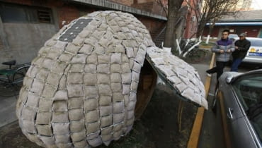 Visitors take photos of an egg-shaped mobile house near its owner Dai Haifei's office building in Beijing December 3, 2010. Dai, who is from central China's Hunan province and cannot afford Beijing's high rental prices, has been living in the house which costs about 6427 yuan ($965). The house is made of bamboo strips, steel bars, heat prevention and waterproof materials, sacks filled with fermented wood chips and grass seeds, as well as one solar-cell panel, local media reported. REUTERS/Petar Kujundzic (CHINA - Tags: BUSINESS SOCIETY)