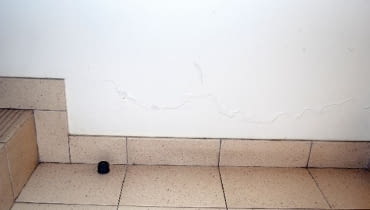 Łuszcząca się farba na ścianie przy podłodze parteru Łuszcząca się farba na ścianie przy podłodze parteru