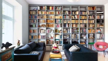 Wygodnym kanapom towarzyszy fotel vintage. Pomiędzy nimi stołek z plecionym siedziskiem - przykład PRL-owskiego designu. Wygodnym kanapom towarzyszy fotel vintage. Pomiędzy nimi stołek z plecionym siedziskiem - przykład PRL-owskiego designu.