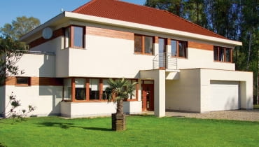 Elewacja: jasny tynk z fragmentami obłożonymi drewnem; Dach: czerwony, zbliżony do koloru drewna; Okna i drzwi: profile i skrzydła zbliżone do barwy drewna; Brama garażowa: biała, dopasowana do barwy tynku elewacyjnego Elewacja: jasny tynk z fragmentami obłożonymi drewnem; Dach: czerwony, zbliżony do koloru drewna; Okna i drzwi: profile i skrzydła zbliżone do barwy drewna; Brama garażowa: biała, dopasowana do barwy tynku elewacyjnego