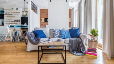 W tym mieszkaniu salon, kuchnia i sypialnia to w gruncie rzeczy jedna, wspólna przestrzeń. Przegrodą są tylko ruchome skrzydła drzwi przesuwnych, które w razie potrzeby mogą odgrodzić pomieszczenie sypialni od reszty mieszkania. Aranżacja mieszkania dla singla