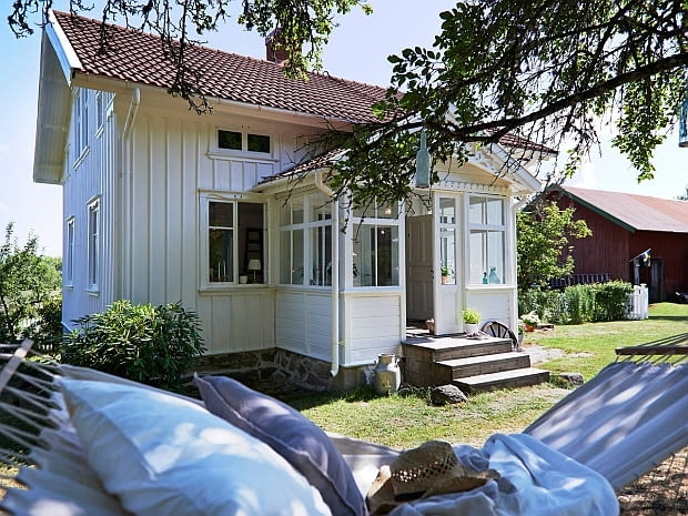 Domek stoi na niewielkim wzniesieniu. Z okien roztacza się piękny widok na okolice. mały domek, drewniany domek, dom w Szwecji, wnętrza, skandynawski styl