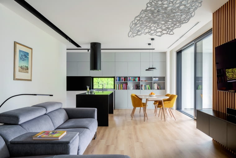 Główną część parteru zajmuje połączona przestrzeń salonu, jadalni i kuchni. Utrzymana jest w jasnych tonacjach, z wyrazistymi aplikacjami czerni. Spokojowi i uporządkowaniu tych wnętrz „podstawia nogę” ekspresyjny sufitowy żyrandol wykonany przez łódzkiego artystę Główną część parteru zajmuje połączona przestrzeń salonu, jadalni i kuchni. Utrzymana jest w jasnych tonacjach, z wyrazistymi aplikacjami czerni. Spokojowi i uporządkowaniu tych wnętrz „podstawia nogę” ekspresyjny sufitowy żyrandol wykonany przez łódzkiego artystę