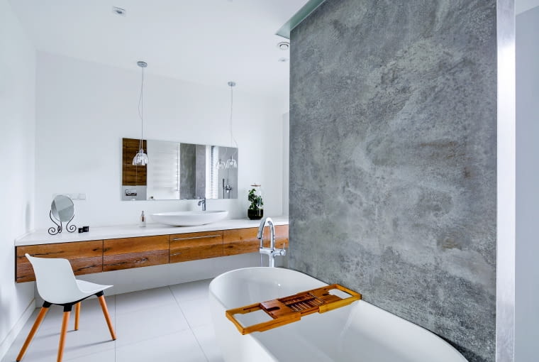 W głównej łazience powtórzono motyw samotnej ściany, tu rozdzielającej wannę od prysznica. Drewniane wykończenie przestrzeni pod umywalką wykonano z dębowych desek podłogowych