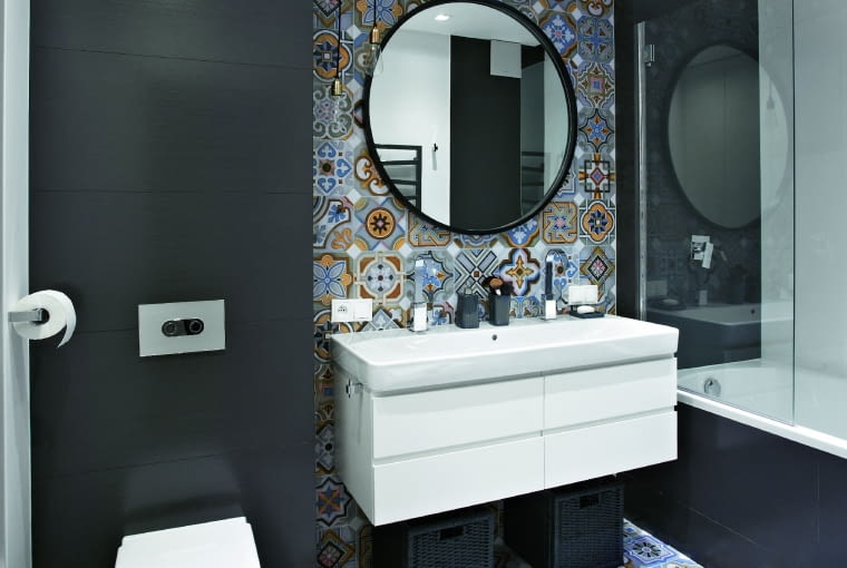 PŁYTKI o wzorach inspirowanych azulejos (firma Vives) zestawiono z gresem w grafitowym odcieniu (Atlas Concorde). W podwójnej umywalce (Koło) zamontowano baterie firmy Paffoni. Kącik ten oświetlają halogeny ukryte za załomem podwieszanego sufitu oraz dwie wiszące lampy-żarówki.