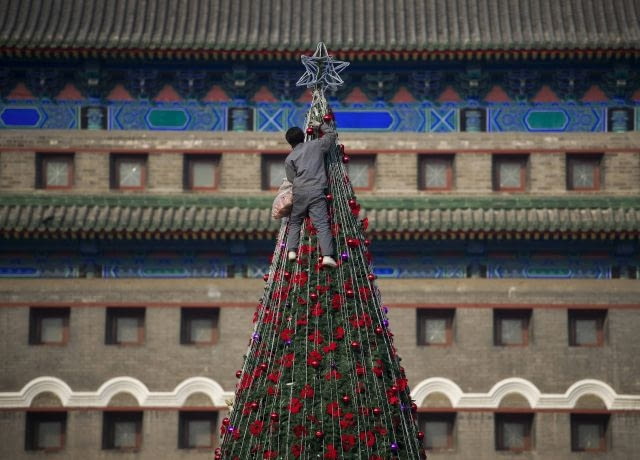 Chiny: Instalacja dekoracji świątecznych na choince w Pekinie A worker installs decorations on a Christmas tree displayed at the Qianmen street in Beijing, China, Sunday, Dec. 13, 2009. (AP Photo/Andy Wong)