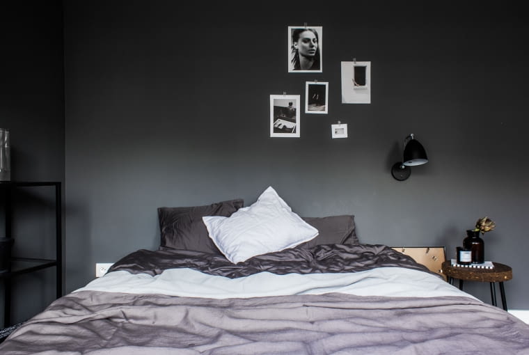 Sypialnia gospodarzy utrzymana jest w ciemniejszych tonacjach, dzięki czemu sprzyja wyciszeniu i jest bardziej intymna. Zdjęcia zawieszone w swobodnej galerii na ścianie nadają wnętrzu osobistego charakteru.