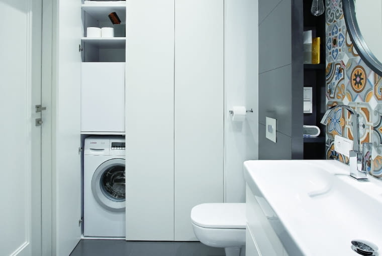 Gładkie jasne fronty bez uchwytów wyglądają jak ściana, dzięki czemu pojemna zabudowa nie rzuca się w oczy.