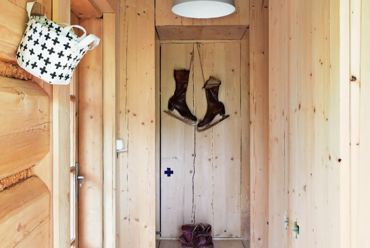 KOLEJNY SPORTOWY AKCENT: w drewnianej sieni wiszą łyżwy wyszukane na targu staroci. Nad wnęką - lampa-dzwon przywieziona z podróży po Szwecji.