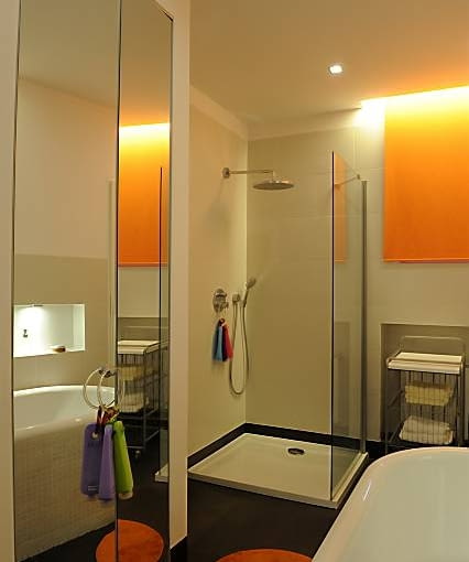 W osłoniętej jedną szklaną ścianką kabinie natryskowej, usytuowanej w narożniku, oprócz rączki prysznicowej zainstalowano tzw. deszczownicę, której strumień działa relaksująco.