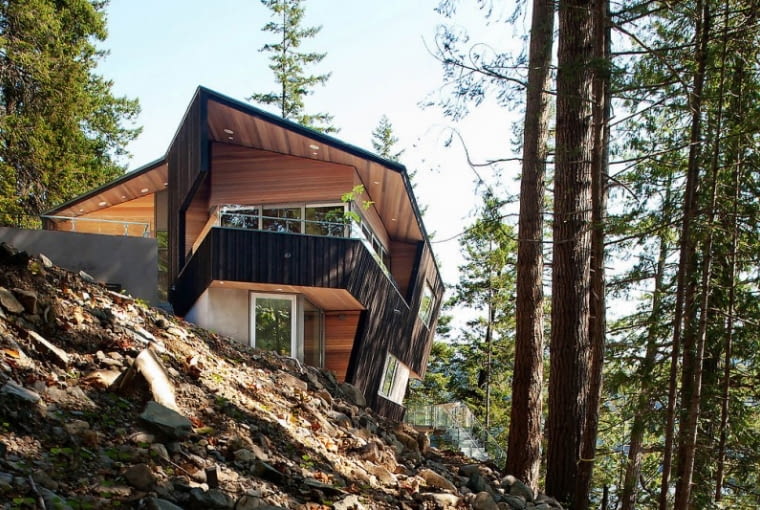 Oryginalna bryła budynku, przypominająca heksagon, to dzieło projektantów ze studia Battersby Howat Architects z pobliskiego Vancouver. Przestrzenny wielokąt zapewnia doskonały widok na całą okolicę. Stromo nachylony i zalesiony stok, u stóp którego znajduje się mała kamienna plaża, okazał się idealnym miejscem na budowę domu dla całej rodziny. dom na urwisku, nowoczesny dom